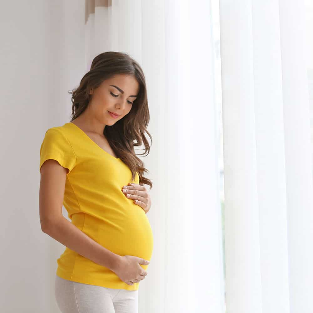 Home-pregnant-woman-yellow-tshirt-white-bkgd-523619266-SQ